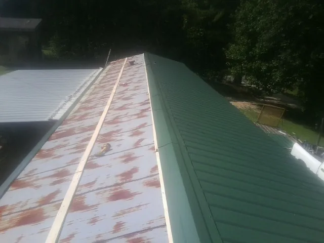 Old rusted panels beside newly installed green metal roofing — Wind Damage Roof Repair by Roofing Brothers in Farmersville