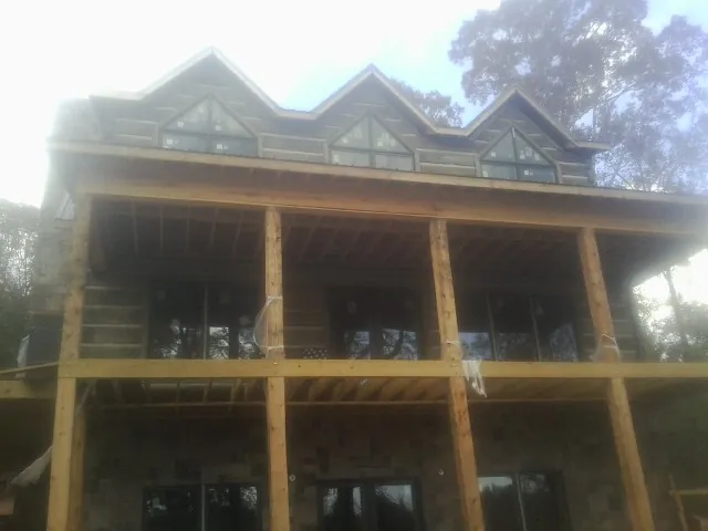 Dormers and porch framing on a large log home under construction — Roof Coating work by our crew in Farmersville