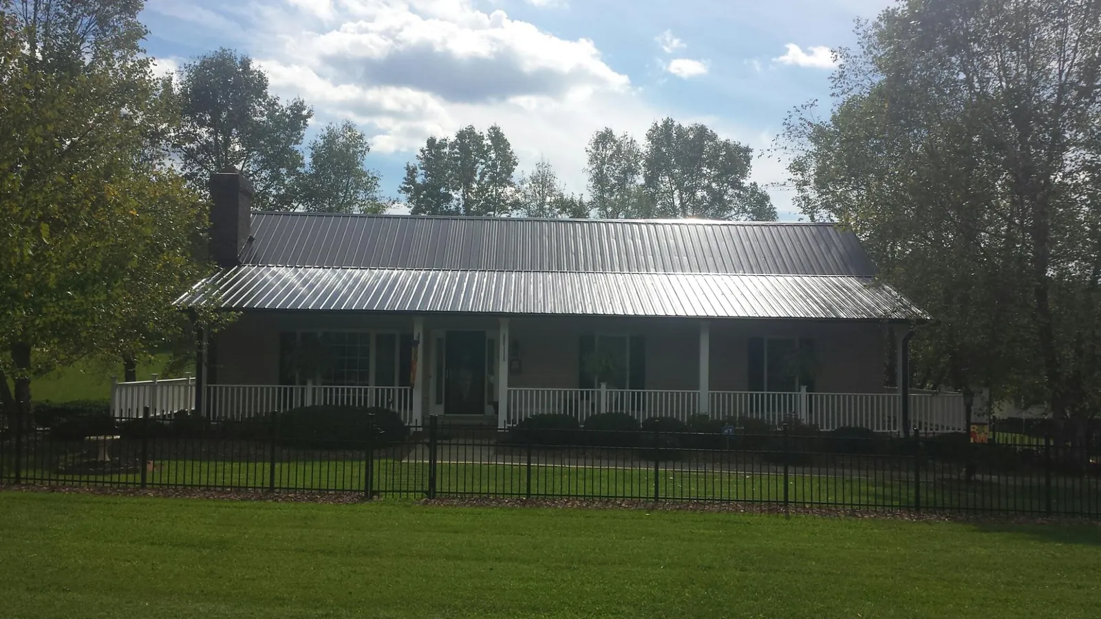 Gray metal roof on a brick ranch with a full width front porch — Gutter Guard Installation work by our crew in Farmersville