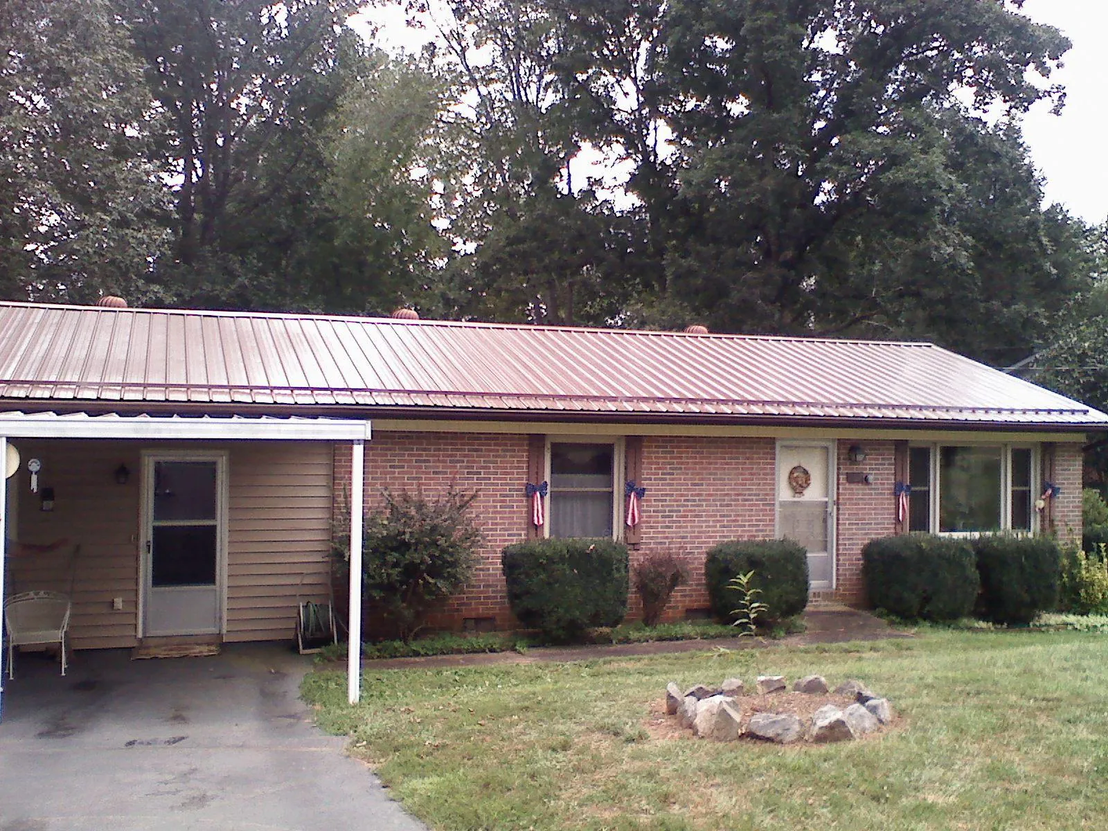 Bronze metal roof and carport on a brick ranch home — Roof Repair work by our crew in Farmersville