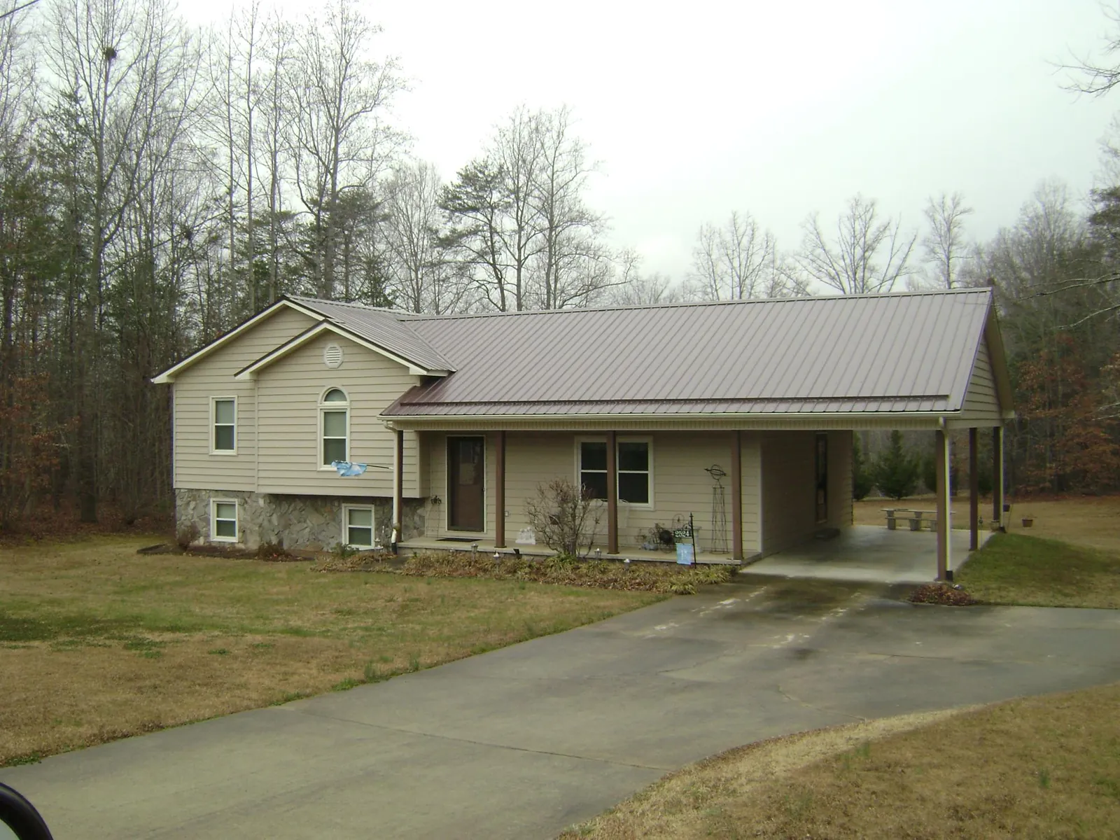 Brown metal roof on a tan split level home with an attached carport in Farmersville