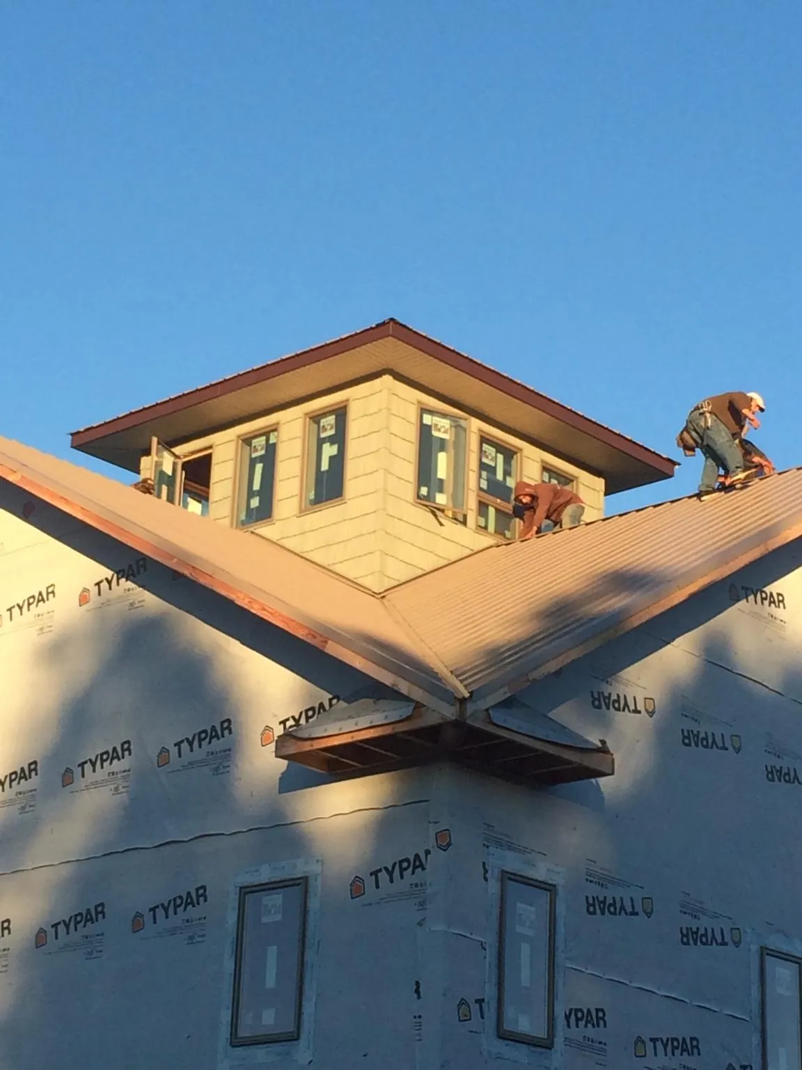Roofers working around a rooftop cupola on a new metal roof at sunset — Roof Waterproofing in Farmersville by Roofing Brothers